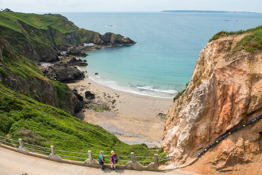 Two women looking at the Grande Greve Bay from La CoupĂ&Acirc;&copy;e, the narrow isthmus which links Greater and Little Sark, Sark island, Channel Islands, Bailiwick of Guernsey, United Kingdom