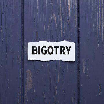 Torn piece of white paper with the word bigotry written in black bold letters