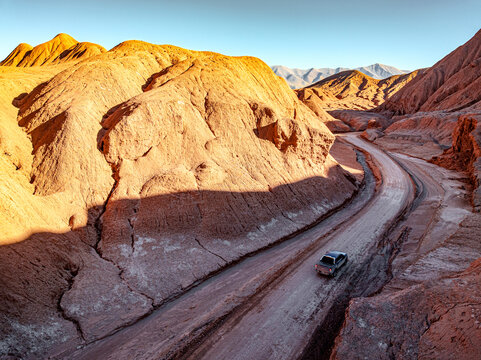 Car on a road alongside fossil cliffs, Labyrinth desert, Puna, Salta, Argentina