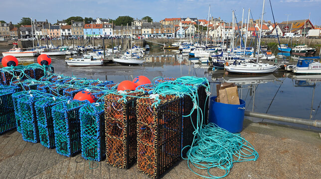 Fishing traps and boats occupy the harbour in Anstruther while the town skyline provides a scenic backdrop in Scotland