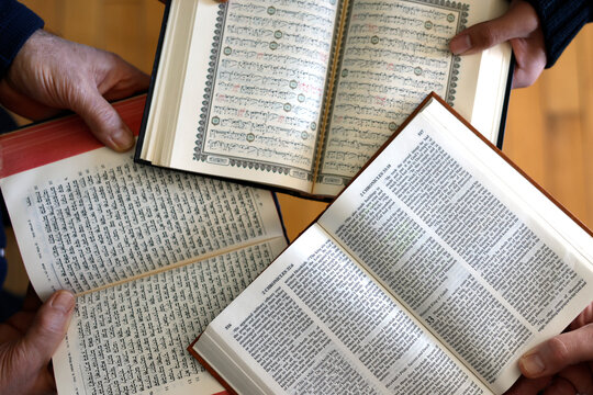 Three monotheistic religions. A Christian, a Jew, and a Muslim reading the Bible, the Torah, and the Quran. Symbol of peace and interfaith dialogue.