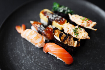 Sushi served on a black plate with various seafood and rice types at a local restaurant