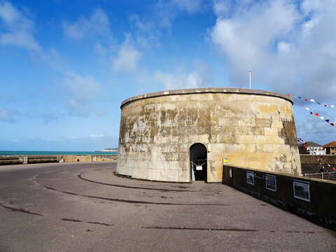 Martello Tower showing coastal view with flag decorations under blue sky in Seaford, East Sussex, United Kingdom