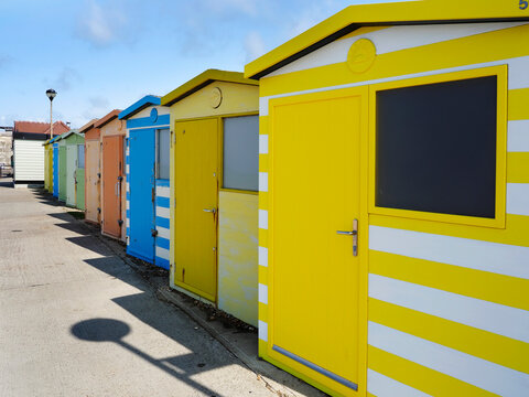 Colorful beach huts stand in a row by the coast in Seaford East Sussex, offering shelter and charm along the shore