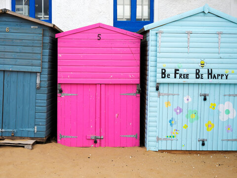 Colorful beach huts stand in a row along the sandy shore of Broadstairs in Kent, inviting visitors to enjoy the seaside