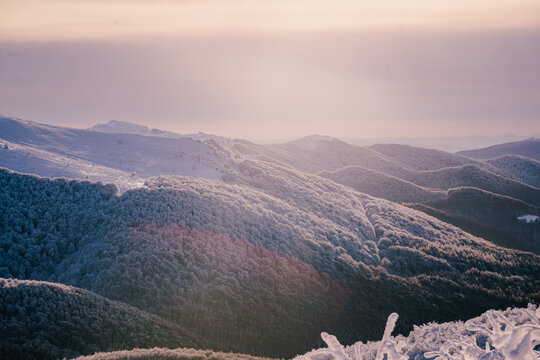 Snow covered ridge trail in the Bieszczady during a cold winter morning with blue sky, golden hour light and panoramic mountain views.
