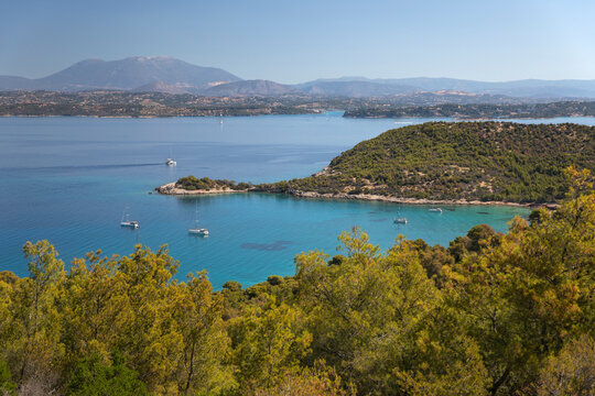 View over Paralia Zogerias beach with crystal clear blue water in bay and anchored yachts, Spetses, Saronic Islands, Greek Islands, Greece, Europe