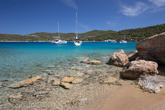 Paralia Zogerias beach with crystal clear blue water and yachts, Spetses, Saronic Islands, Greek Islands, Greece, Europe