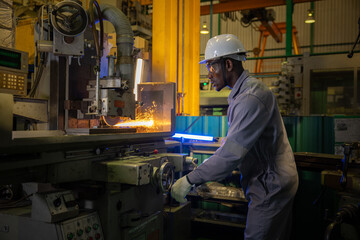 Confident african worker control lathe machine showing focus and serious expression while metal sparks fly in industrial factory manufacturing heavy steel parts with precision