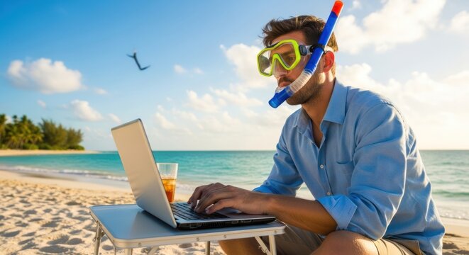 Man working on laptop at beach with snorkeling gear.