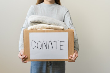 Recycling, Donation for poor, asian young woman pack, hand in holding donate box full with second hand clothes, charity helping and needy people. Reuse recycle, moving of object on white background. © KMPZZZ