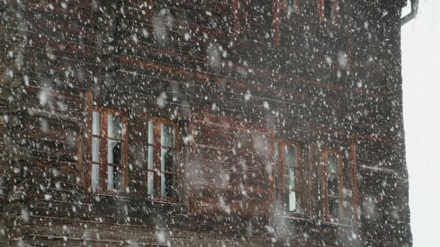 heavy snow fall on the window of a old wooden swiss chalet