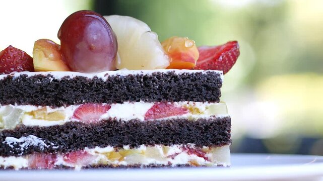 Close up layered chocolate cake with fresh fruit topping slowly moving