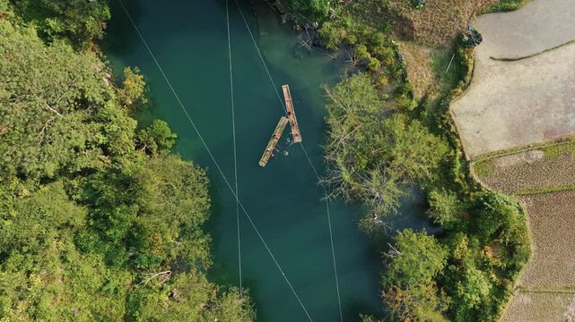 Aerial view of tourists enjoying bamboo rafting and swimming in the blue waters of Hang Than Lim, Yen Minh, Ha Giang, Vietnam.. A popular activity for visitors.