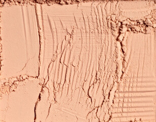 Fototapeta premium Tactile makeup powder texture with rough pressed surface and scattered cosmetic particles. Neutral beige beauty background ideal for cosmetic branding, packaging design, editorial projects