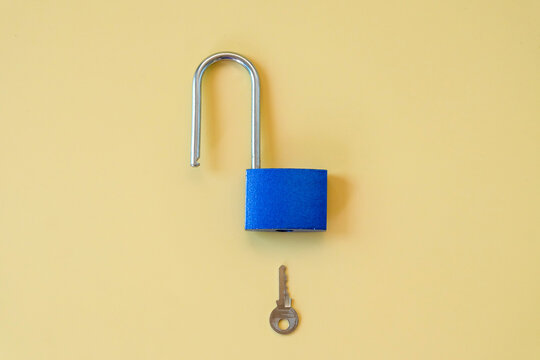 Unlocked blue padlock with key on color background.