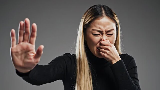 Woman coughing and gesturing stop on a gray background
