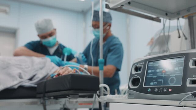 Surgeons performing a medical procedure in a hospital operating room while the patient lies on an operating table. Medical team in sterile uniforms working with surgical equipment in a controlled