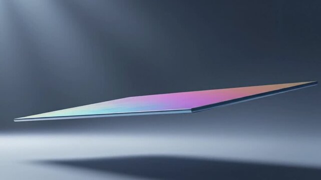 Close-up shot of a colorful, iridescent, flat, rectangular object with a gradient of purple, pink, and blue hues on a dark gray background with a beam of light.