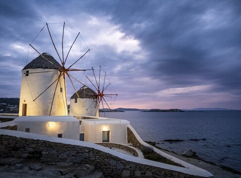 Illuminated windmills, Kato Milli, at sunset, dramatic cloudy sky, Mykonos Town, Mykonos, Greece