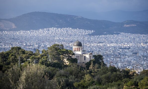 View over houses of Athens in the evening light, with National Observatory at Philopappos Hill, in the evening light, Athens, Attica, Greece