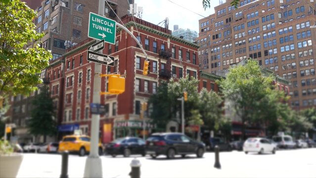 Manhattan Midtown street New York City, United States. Red brick house, building architecture in Chelsea residential district. People pedestrian, yellow taxi car on crossroad. Lincoln Tunnel road sign