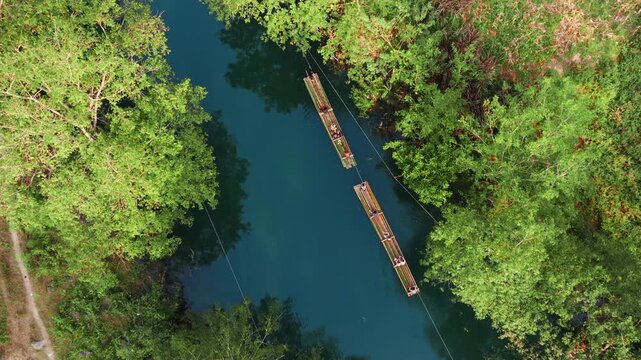 Aerial view of tourists enjoying bamboo rafting and swimming in the blue waters of Hang Than Lim, Yen Minh, Ha Giang, Vietnam.. A popular activity for visitors.