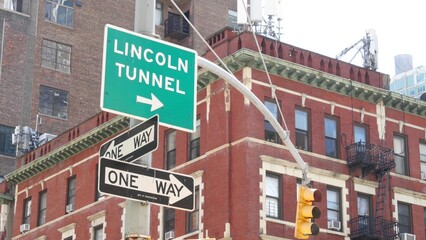 Obraz premium New York City Lincoln Tunnel street sign in Manhattan Midtown, United States. Urban road sign in american city, traffic sign in NYC. Red brick building architecture, Chelsea district near Hudson Yards