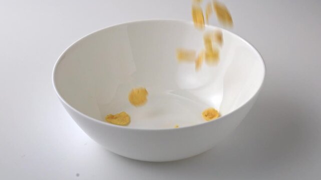 Cereal falls into a white bowl creating a splash at breakfast time in a simple kitchen setting