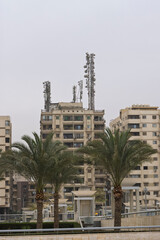 Urban apartment building with cell towers and palm trees near Museum of Civilisation in Cairo, Egypt