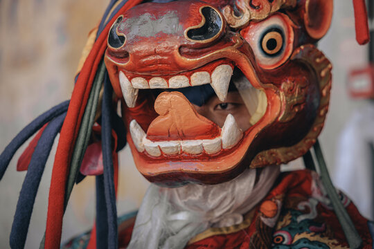 Jakar Dzong, Bhutan - 24 September 2025: View of a vibrant red-toned mask with sharp white teeth and colorful tassels, revealing a glimpse of eyes, creating an intense and captivating portrait.