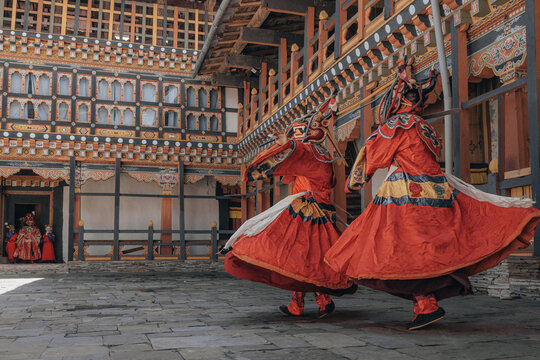 Jakar Dzong, Bhutan - 24 September 2025: View of vibrant red-clad dancers swirling amidst the ornate architecture of the Dzong, their movements echoing the intricate details of the ancient fortress.