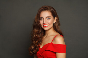 Naklejka premium Successful brunette woman with trendy make-up and brown curly hair wavy hairstyle and red lips makeup on black background