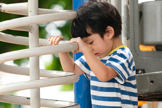 A cute and cheerful little Asian boy as he plays on an outdoor playground. The kid is laughing heartily while enjoying the activities in a public park, a genuine moment of happy childhood