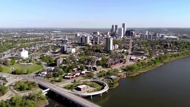 Aerial shot of the Tulsa Oklahoma skyline and Arkansas River, green riverbanks and the 21st Street Bridge.
