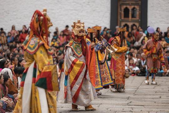 Thimphu, Bhutan - 28 September 2025: View of vibrant dancers in traditional masks and colorful robes perform at Tashichho Dzong, a spectacle of cultural richness against a backdrop of eager onlookers.