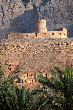Al Qala's Fort, overlooking the village and castle of Bukha, view of the castle between the mountains and palm trees. Musandam, Oman