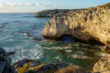 Dramatic coastline near Waenhuiskrans Cave, Arniston: towering cliffs meet ocean waves in pristine Overberg seascape, Western Cape, South Africa. Ideal for nature, travel, and adventure visuals.