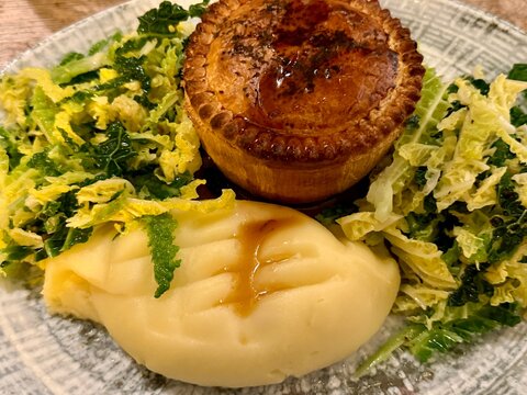 Close-up of an traditional British savoury pie with mashed potato, cabbage and gravy