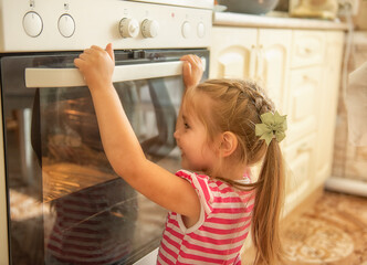 cute little girl with braids curiously peeking into the oven to see what is baking. cozy kitchen interior, warm home atmosphere, natural candid family moment.