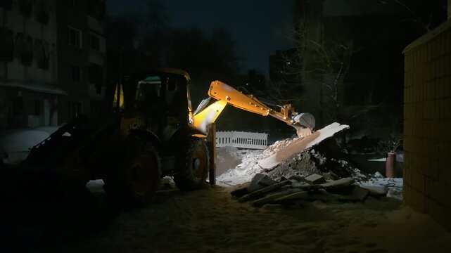 Yellow Excavator Digging at Night in Winter | Urban Pipeline Replacement Construction Work | Backhoe Loader Operating on City Street with Snow and Debris
