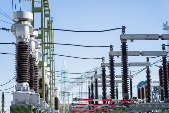 High voltage electrical substation with insulator stacks, busbars and overhead conductors on steel frames, modern power grid infrastructure and energy security theme