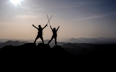 Hiking Partners Raising Trekking Poles On Peak Victory Moment