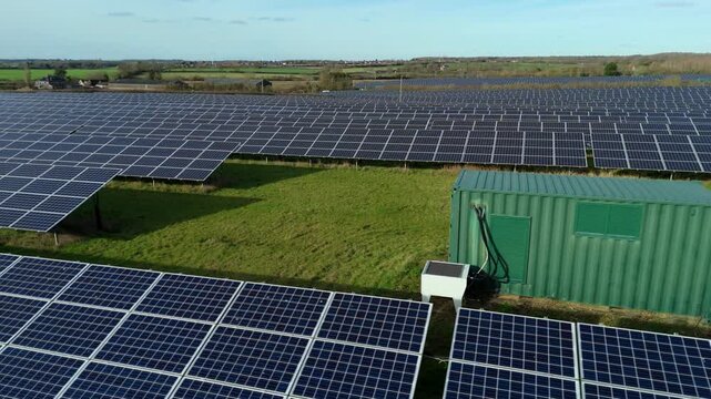 Close-up aerial drone view of a vast photovoltaic solar array integrated with a high-capacity battery energy storage system (BESS) site in the UK.