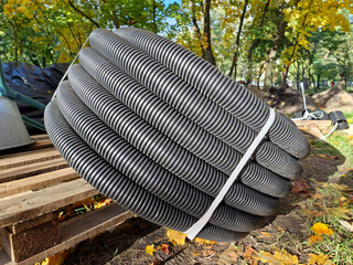Black flexible plastic corrugated pipe lies on construction site