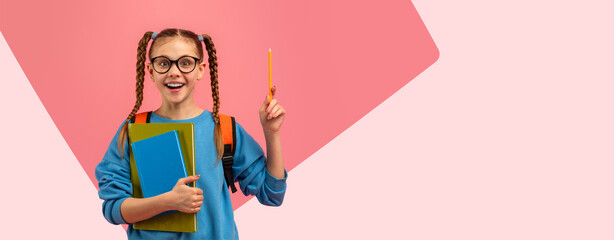 A girl stands with a backpack on her back. She holds a few books in one hand and a pencil in the other. She smiles and seems excited. The background has a light pink color. © Prostock-studio