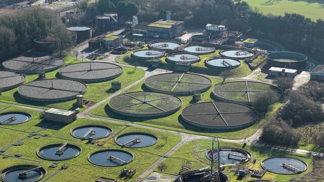 Aerial overview of a major UK sewage facility, emphasizing the intricate network of sedimentation ponds and clarifiers in a rural setting.