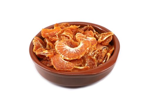 Dried segments of clementines in a ceramic bowl on white background.