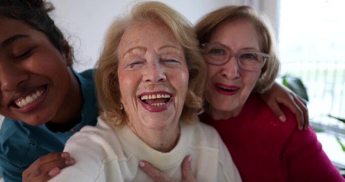 Point of view of three diverse women from different generations smiling and laughing together while taking a selfie video, showing love, happiness, and family connection in a joyful moment