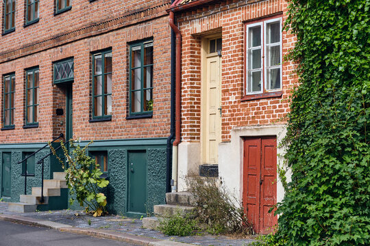 Helsingborg, Sweden - 12 August 2025: View of aged brick buildings with varied painted doors and climbing ivy, reflecting a quaint and colorful Nordic street scene.